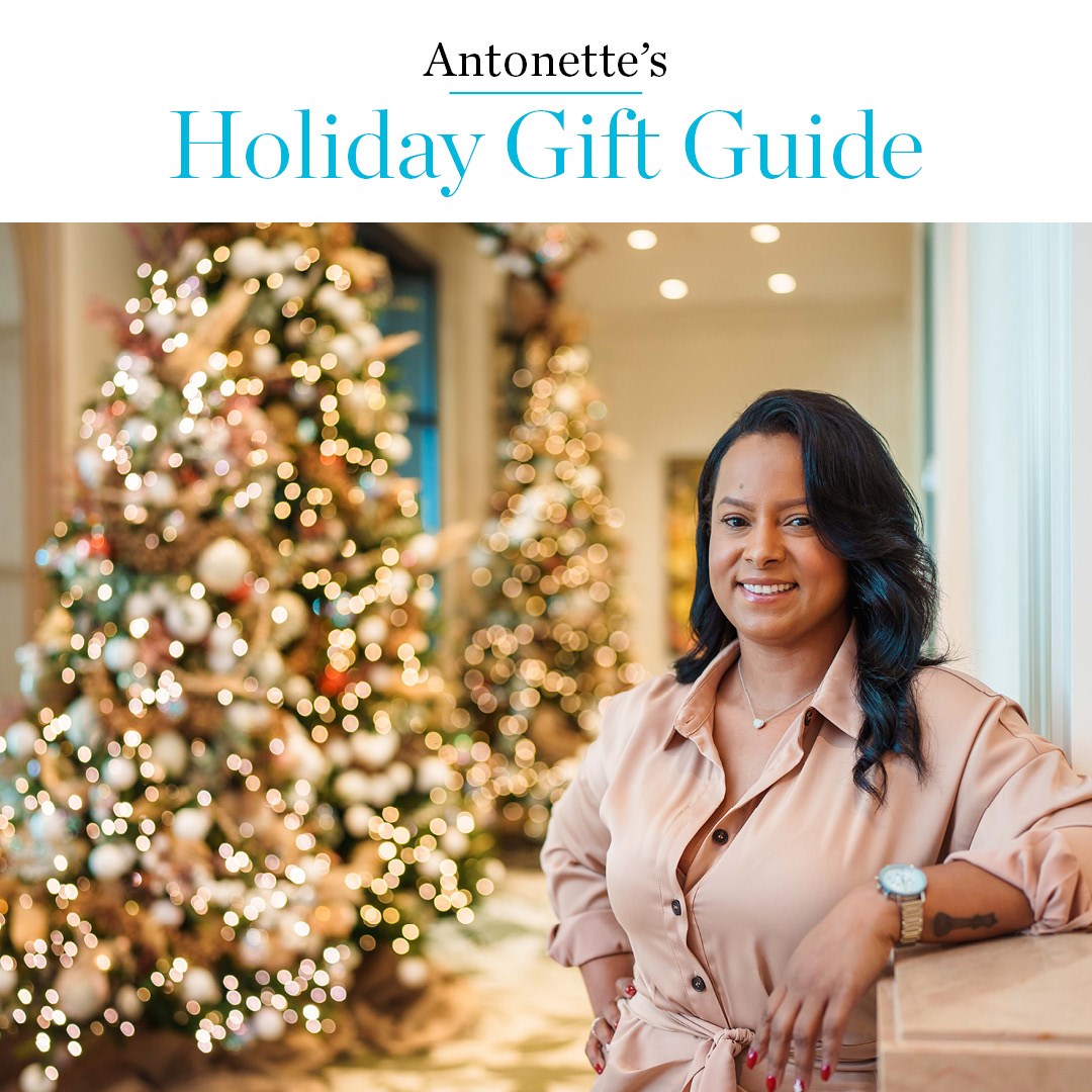 Woman of colour leaning on ledge in front of Christmas tree