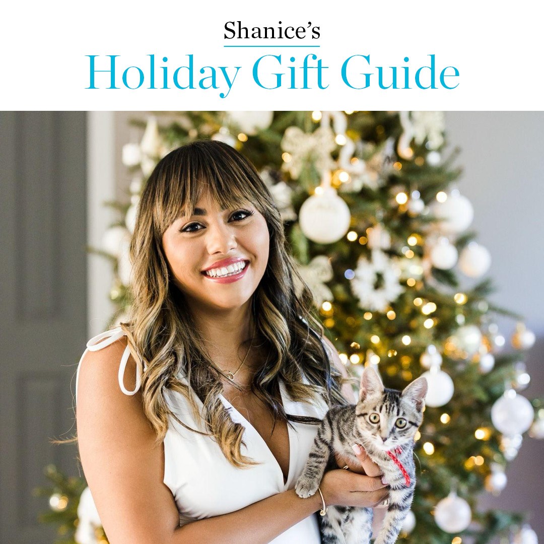 woman of colour smiling with cat in front of Christmas tree